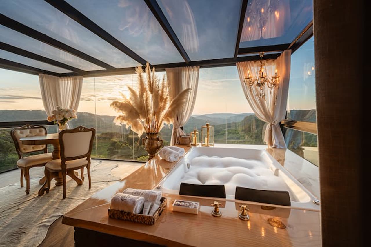 Hot tub under a glass roof with a valley view at dusk